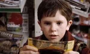 Chłopiec z filmu "Charlie i fabryka czekolady" trzyma złoty bilet. Freddie Highmore w tej roli to początek jego kariery w filmach, serialach i programach.