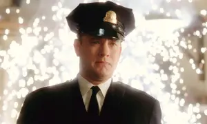 Tom Hanks w mundurze strażnika w jednym z jego filmów. Tło rozświetlone jest fajerwerkami.