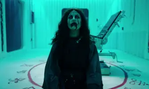 Przerażająca postać z makijażem i krwią na twarzy, otoczona symbolami na podłodze. Scena z serialu Van Helsing, obsada w mrocznym klimacie.