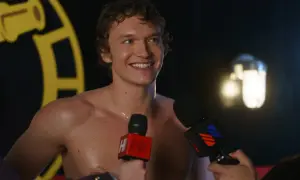 Uśmiechnięty Connor Storrie, bez koszulki, udziela wywiadu. W tle widać żółte logo.