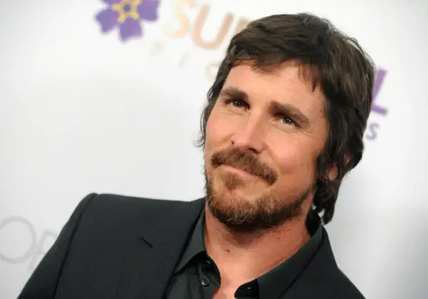 Christian Bale z brodą i w garniturze, znany z wielu świetnych christian bale filmów.