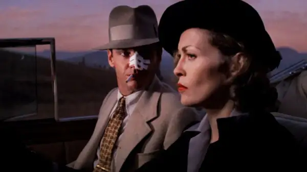Jack Nicholson z plastrem na nosie i papierosem w ustach, obok Faye Dunaway w kapeluszu. Scena z jednego z filmów Romana Polańskiego.