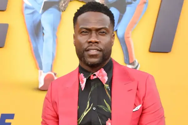 Kevin Hart w czerwonej marynarce i kwiecistej koszuli. Jego wzrost jest często tematem żartów, ale jego talent komediowy jest ogromny.